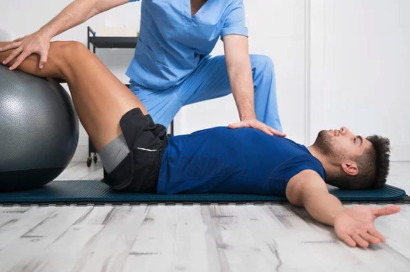 Physical therapist assisting patient with leg stretch using an exercise ball
